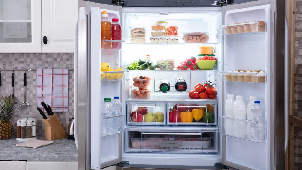 Refrigerator with open doors, full of fresh fruits, vegetables, and a lot of eggs